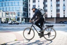 Male cyclist commuting in the city, wearing a backpack for cycling